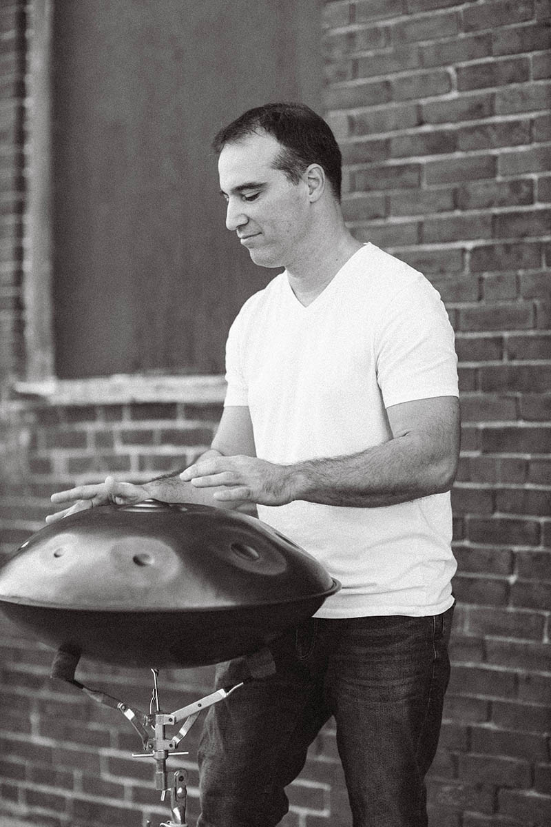 Gabe Cabral performing on the handpan in front of a brick wall.